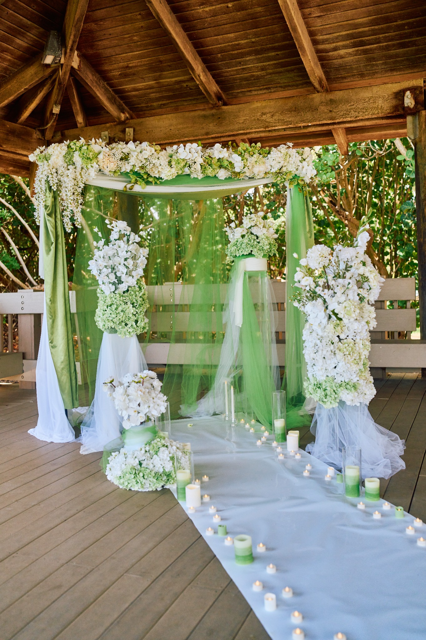 Evergreen Vows white flowers and green drapery in a wooden pavilion